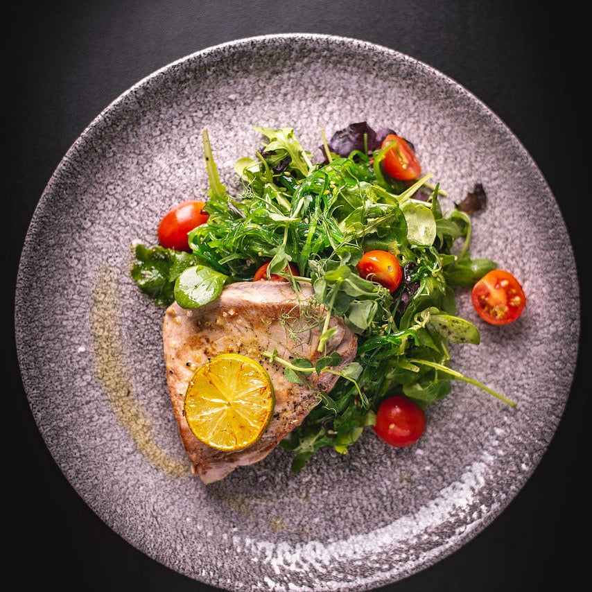 Plated dish with grilled tuna fish and salad on a dark background